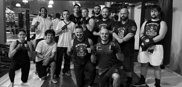 Black and white portrait of a dance instructor posing in front of a dark background.