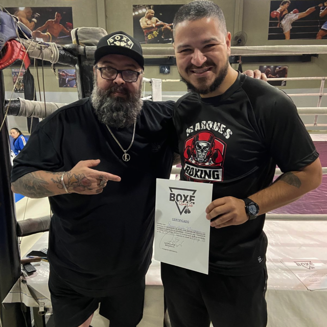 Photo of a silhouette of 2 dancers posing in front of a red curtain.