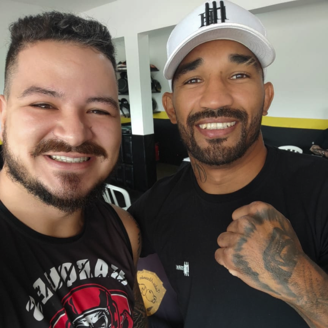 Photo of a silhouette of 2 dancers posing in front of a red curtain.