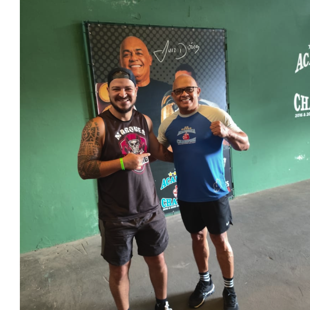 Photo of a silhouette of 2 dancers posing in front of a red curtain.